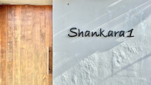 A wooden door and a wall with the name 'Shankara1' in black letters.