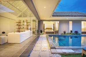 Una habitación de hotel moderna con pared de vidrio, piscina y ambiente luminoso.