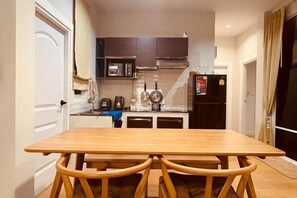 Una cucina compatta con un tavolo e sedie in legno, un forno a microonde e un frigorifero.