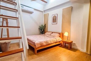 A bedroom with a bed, bedside table, lamp, and a wooden ladder. - child shill pool villa (Hua Hin)