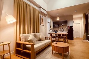 Una sala de estar moderna con un sofá, una mesa redonda de centro, una mesa de comedor con sillas, una zona de cocina y una escalera.