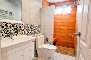 A bathroom with a white sink, toilet, and vanity, a patterned backsplash, and wooden walls. - child shill pool villa (Hua Hin)
