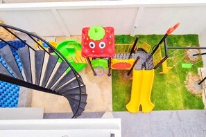 A spiral staircase leading to a balcony with a view of a children's play area. - child shill pool villa (Hua Hin)