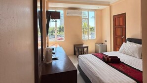 A hotel room with a bed, a desk, and a TV mounted on the wall. - Tomato Motel (Langkawi)