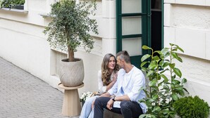 Una pareja sentada en escalones exteriores frente a un edificio con un letrero que dice 'Hotel Botanic'.
