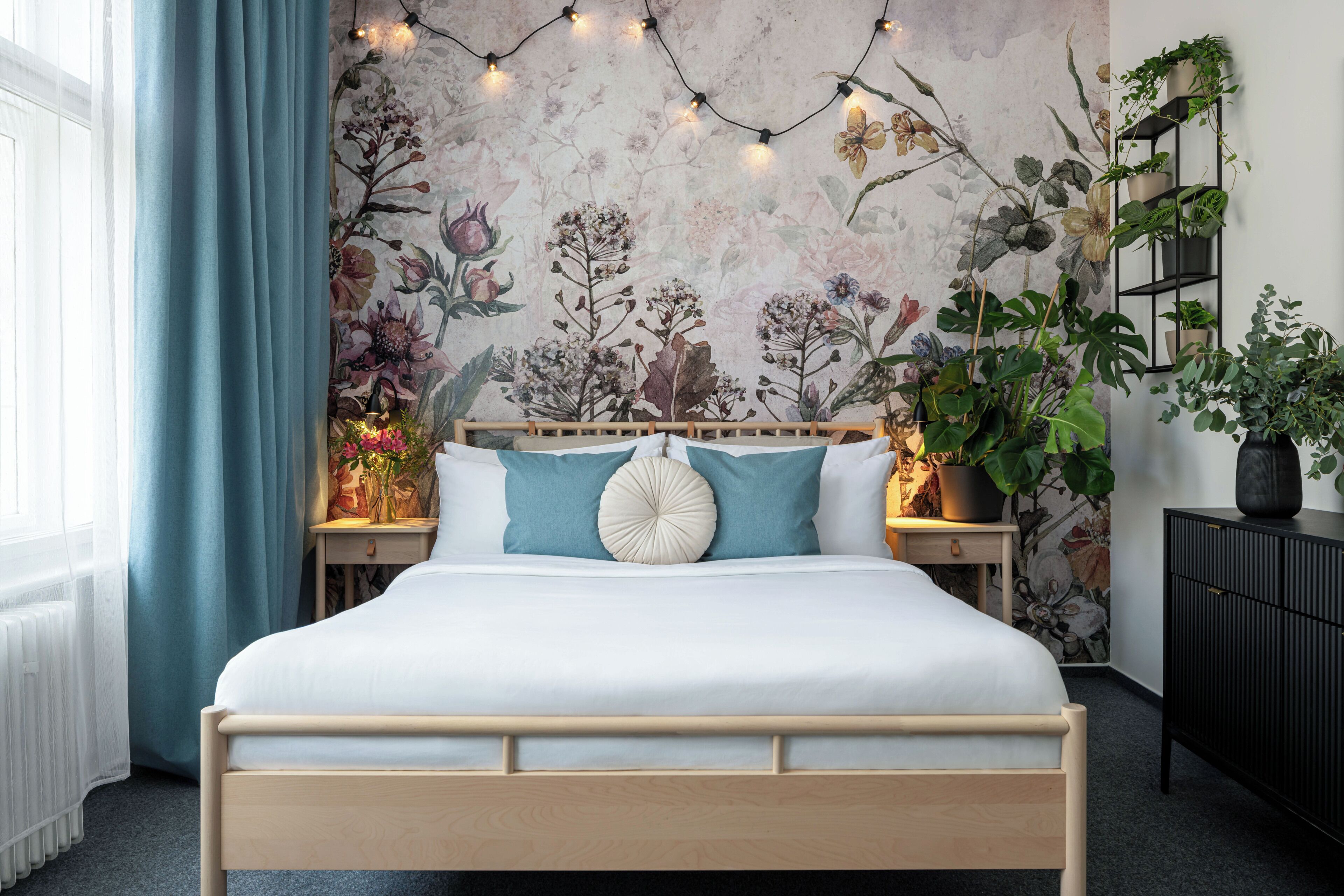 Een slaapkamer met een bed, nachtkastje, kaptafel en een wand met een bloemenreliëf.