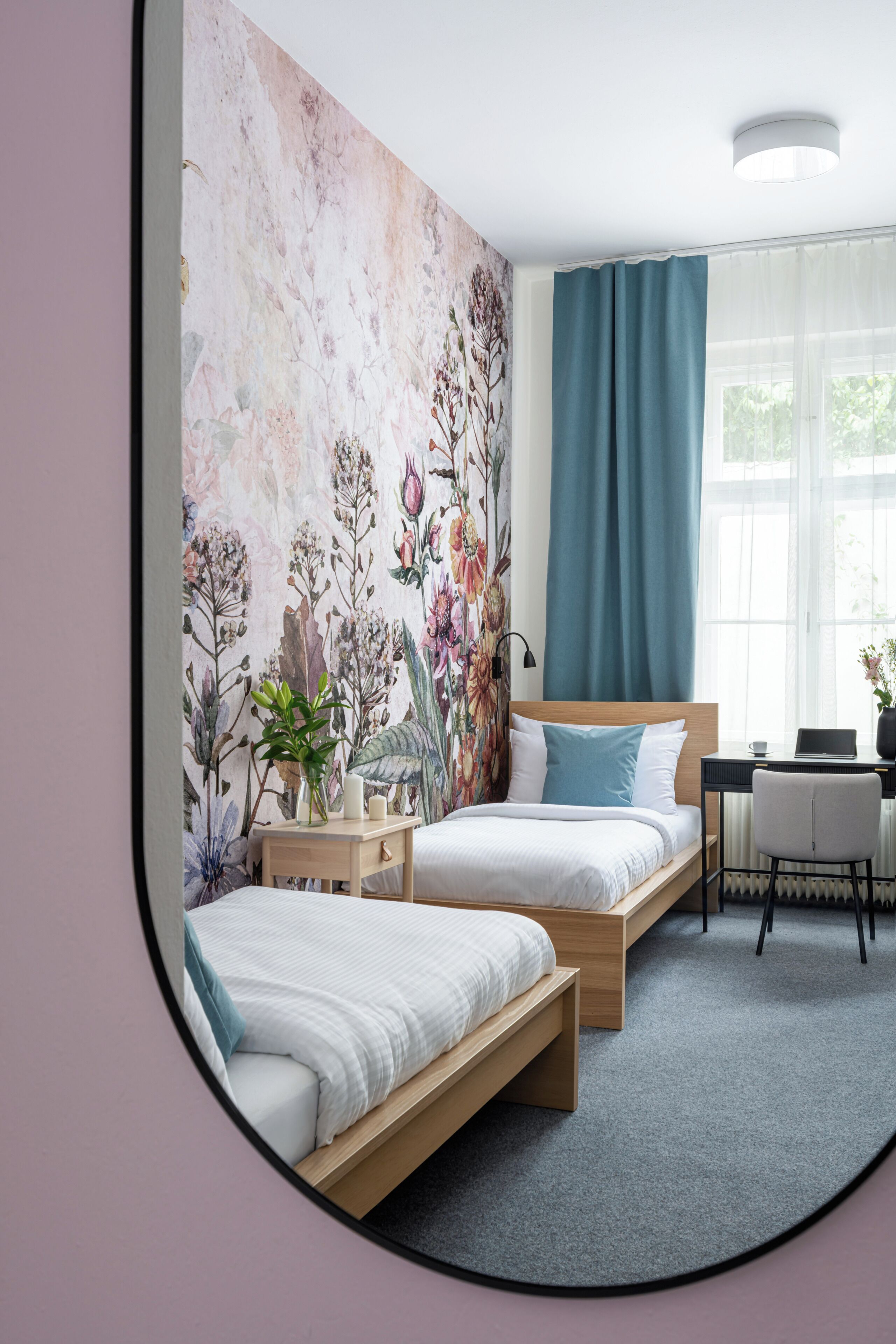 A bedroom with two beds, a desk, and a window with curtains.