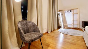 A room with a patterned armchair, a wooden floor, a round rug, and a wardrobe with a ladder. - Stylish Home in Vienna’s Central 9th District (Vienna)