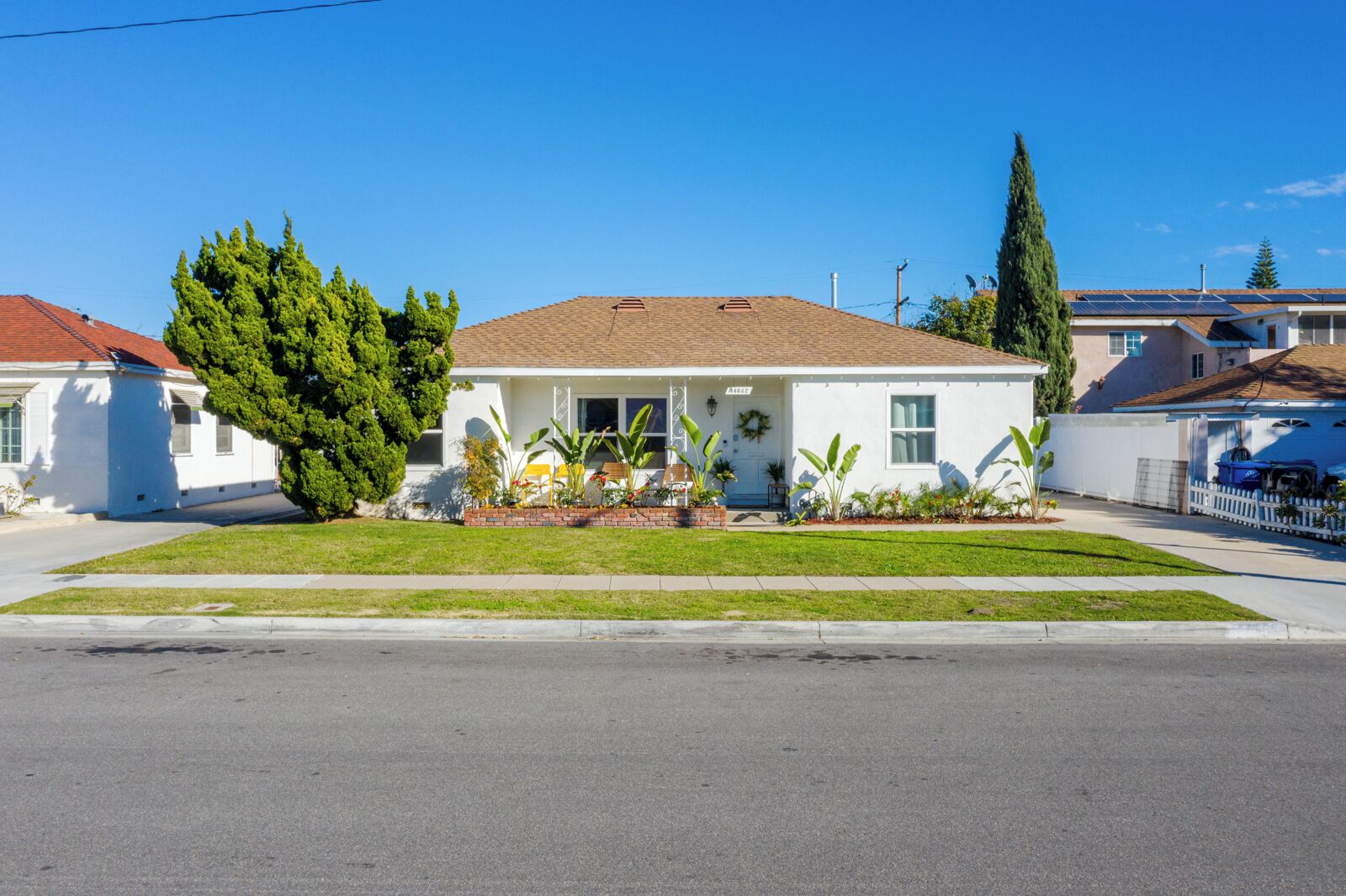 A single-story house with a front yard, a garage, and a solar panel on the roof.