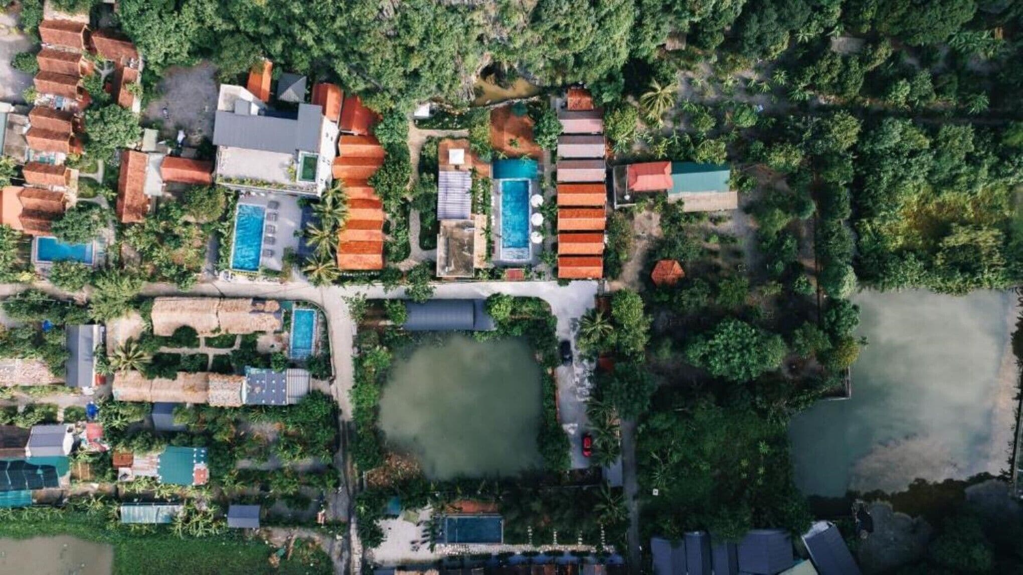 An aerial view of a resort with multiple buildings, swimming pools, and lush greenery.