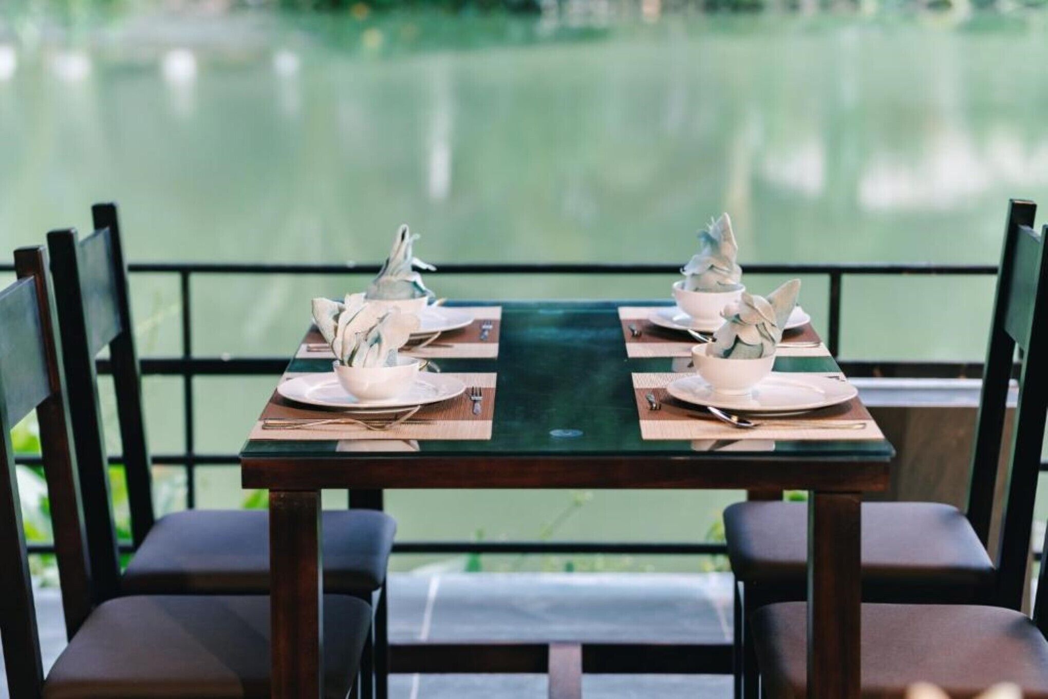 A dining table set for two with a view of a calm body of water.