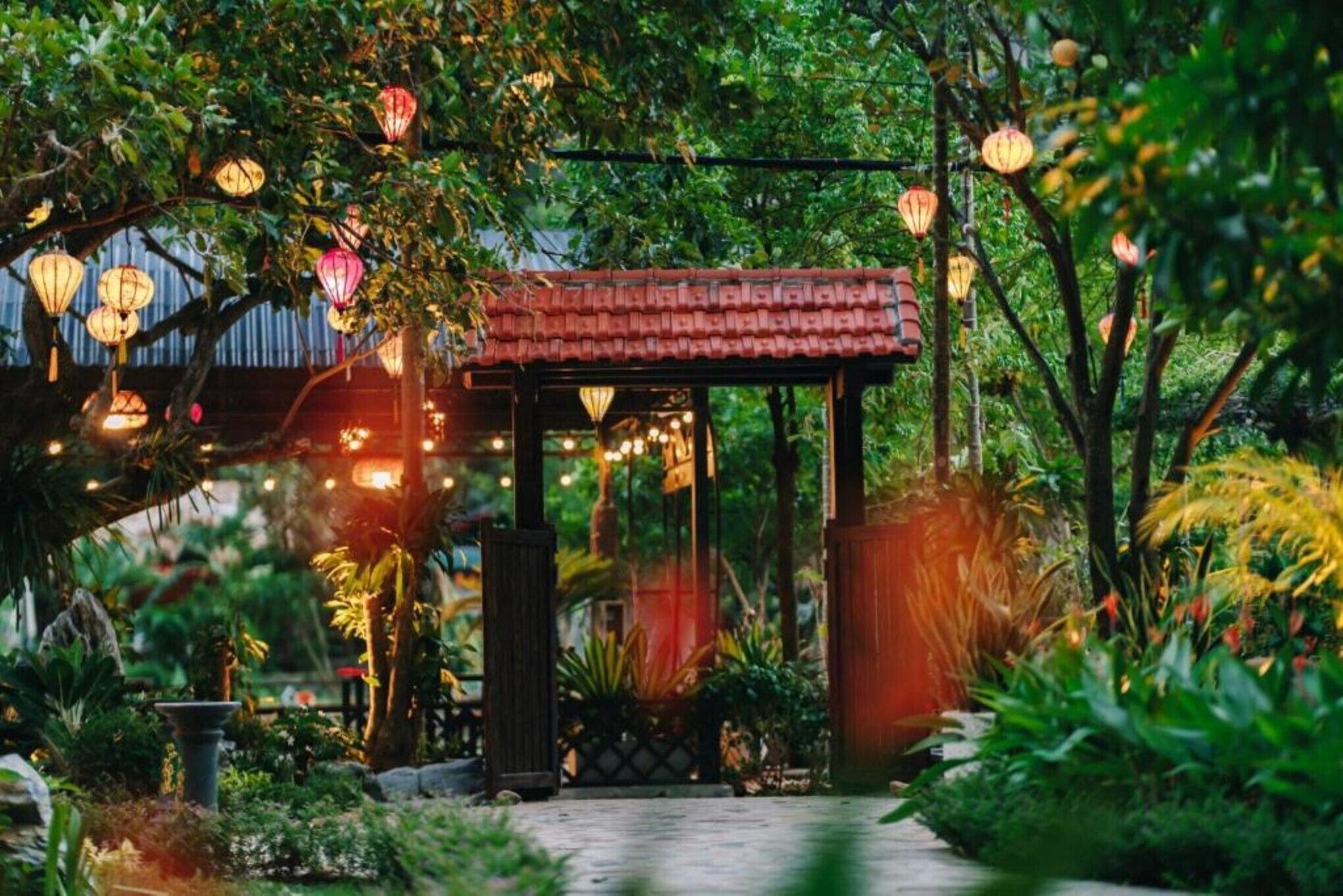 A garden with a gazebo, lanterns, and lush greenery.