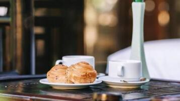 A table with a white vase containing a plant, a plate with pastries, and a cup.