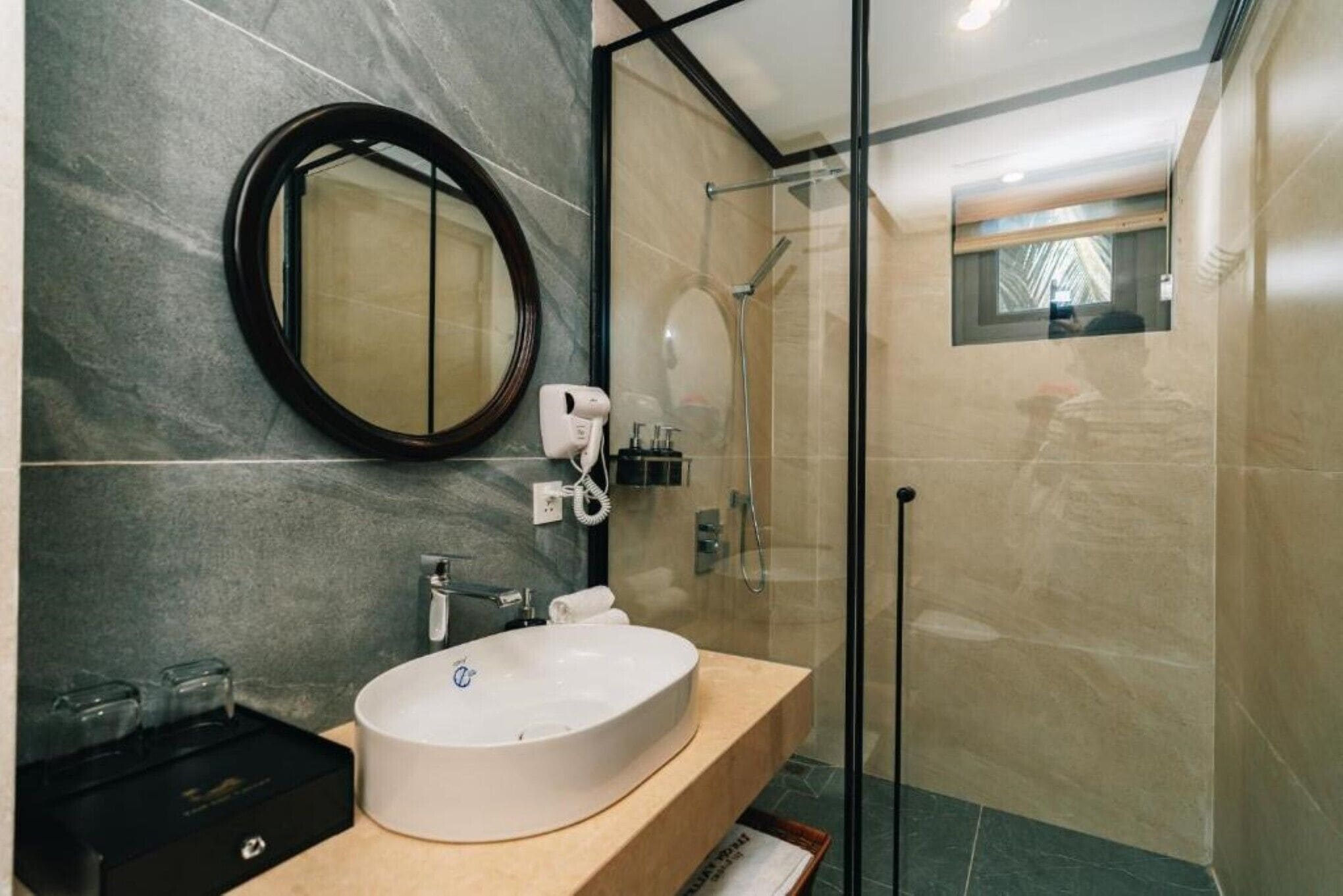Un baño moderno con un espejo redondo, un lavabo y una cabina de ducha con paredes de vidrio.