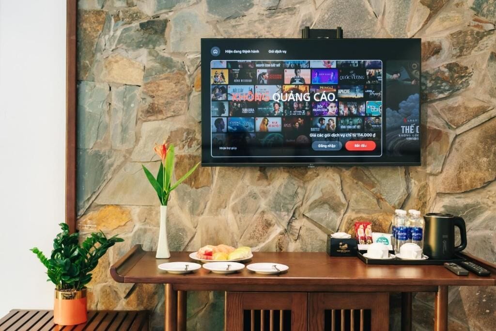 Una televisione fissata a una parete in pietra mostra una selezione di film.