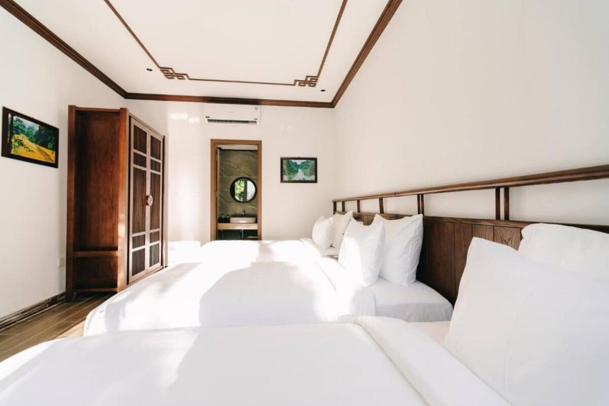 Quarto de hotel com uma cama grande, cabeceira de madeira, um guarda-roupa e um banheiro pequeno.