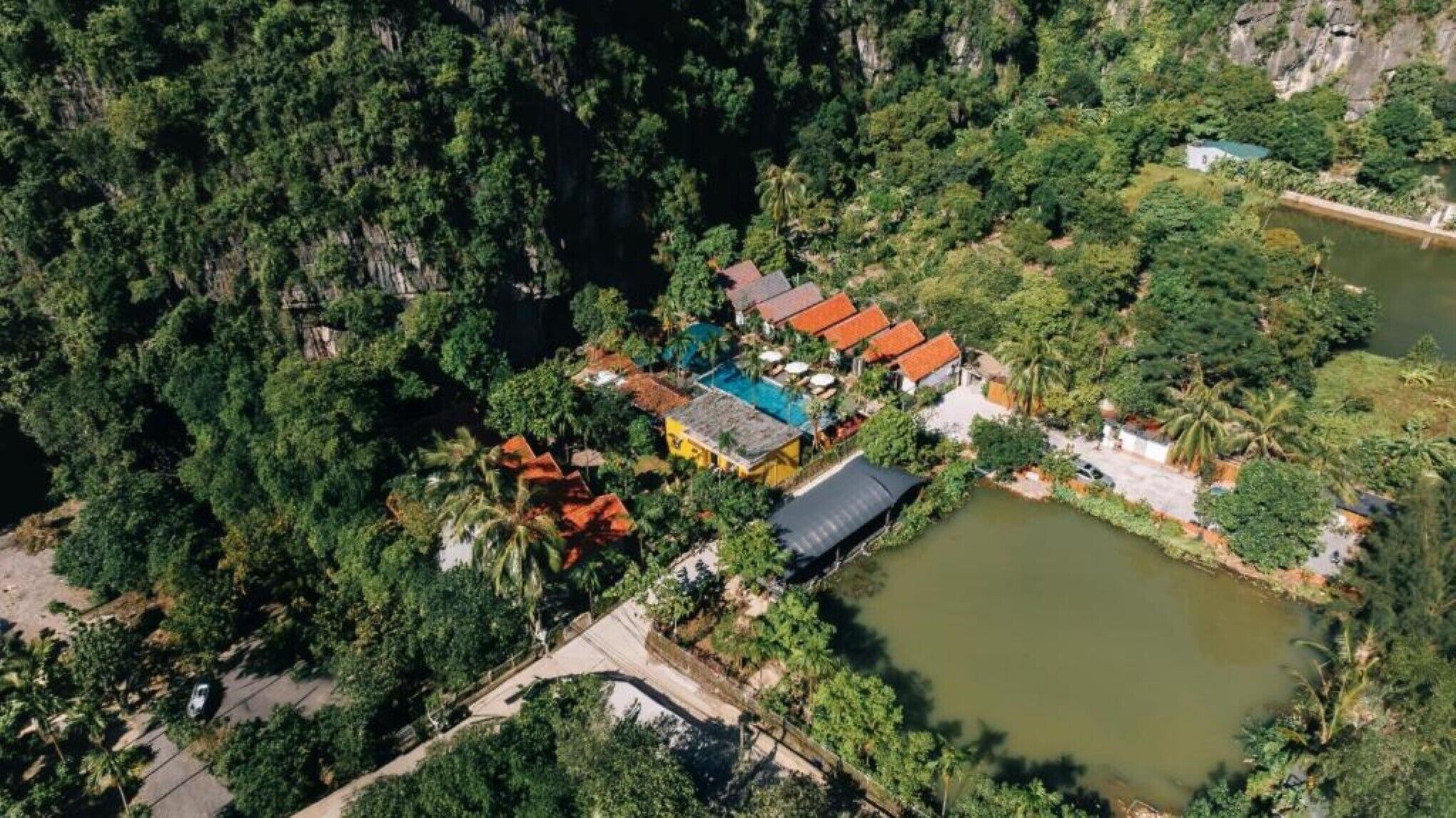 An aerial view of a resort with multiple buildings, a swimming pool, and a large body of water.