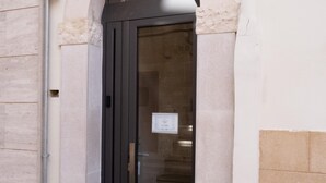 A building entrance with a dark door, a stone archway, and a tiled ground. - 18zero2 Luxury Rooms (Bari)