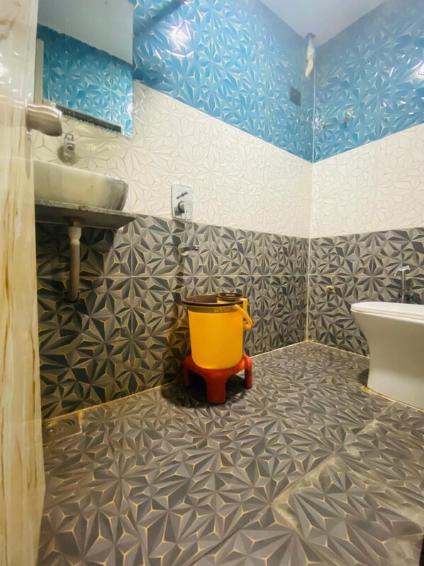 A bathroom with a geometric patterned tile design, a toilet, and a sink. - Hotel Rising Gest (Ahmedabad)