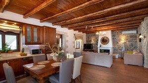 A spacious living area with a wooden ceiling, a stone wall, and a fireplace.