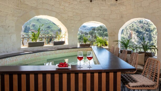 A poolside bar with a view of a mountainous landscape, stone walls, and wicker furniture. - Geroulios Kastro Villa II-Heated* Pool & Jacuzzi (Chania)