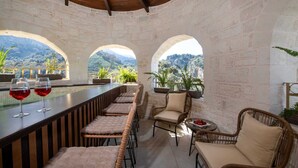A bar area with a long counter, cushioned seating, and a view of mountains through arched openings. - Geroulios Kastro Villa II-Heated* Pool & Jacuzzi (Chania)