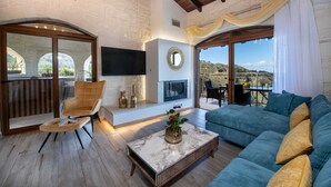 A spacious living room with a fireplace, a sofa, a coffee table, and a TV mounted on the wall. - Geroulios Kastro Villa II-Heated* Pool & Jacuzzi (Chania)