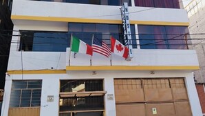 A multi-story building with a yellow and white facade, featuring a storefront with a sign that reads "HOSTEL." - Hotel Residencia Inn Cuzco (Cusco)