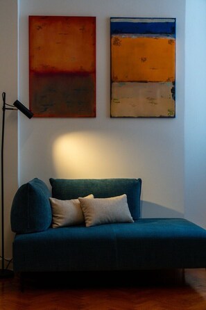 A room with a blue sofa, two pillows, and two abstract paintings on the wall. - Ca' Marcello Levante (Venezia)
