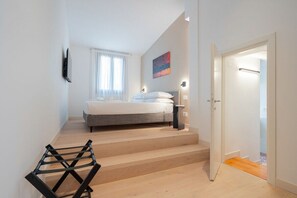 A bedroom with a bed, a staircase, a door, and a wall-mounted light fixture. - Ca' Marcello Levante (Venezia)