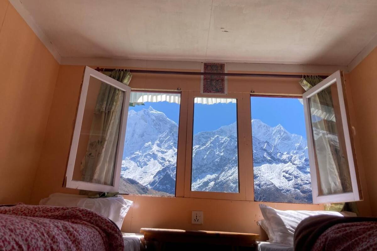 Ein Zimmer mit Bett, Schreibtisch und Fenster mit Bergblick.