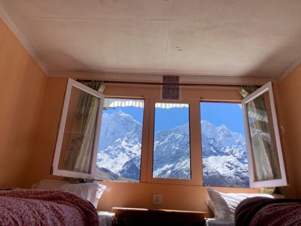 Una habitación con cama, escritorio y ventana con vistas a la montaña.