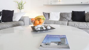 Un soggiorno moderno con un tavolino rotondo, una ciotola di frutta e una rivista.