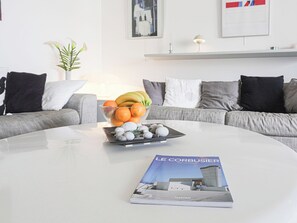 A modern living room with a round coffee table, a bowl of fruit, and a magazine. - Parc Massolin by Interhome (Roquebrune Cap Martin)