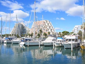 A marina with several yachts docked, surrounded by modern buildings with balconies and a clear blue sky. - Le Saint Clair by Interhome (La Grande Motte)