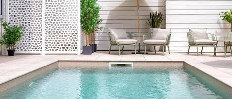 Una piscina al aire libre, sombrillas, tumbonas