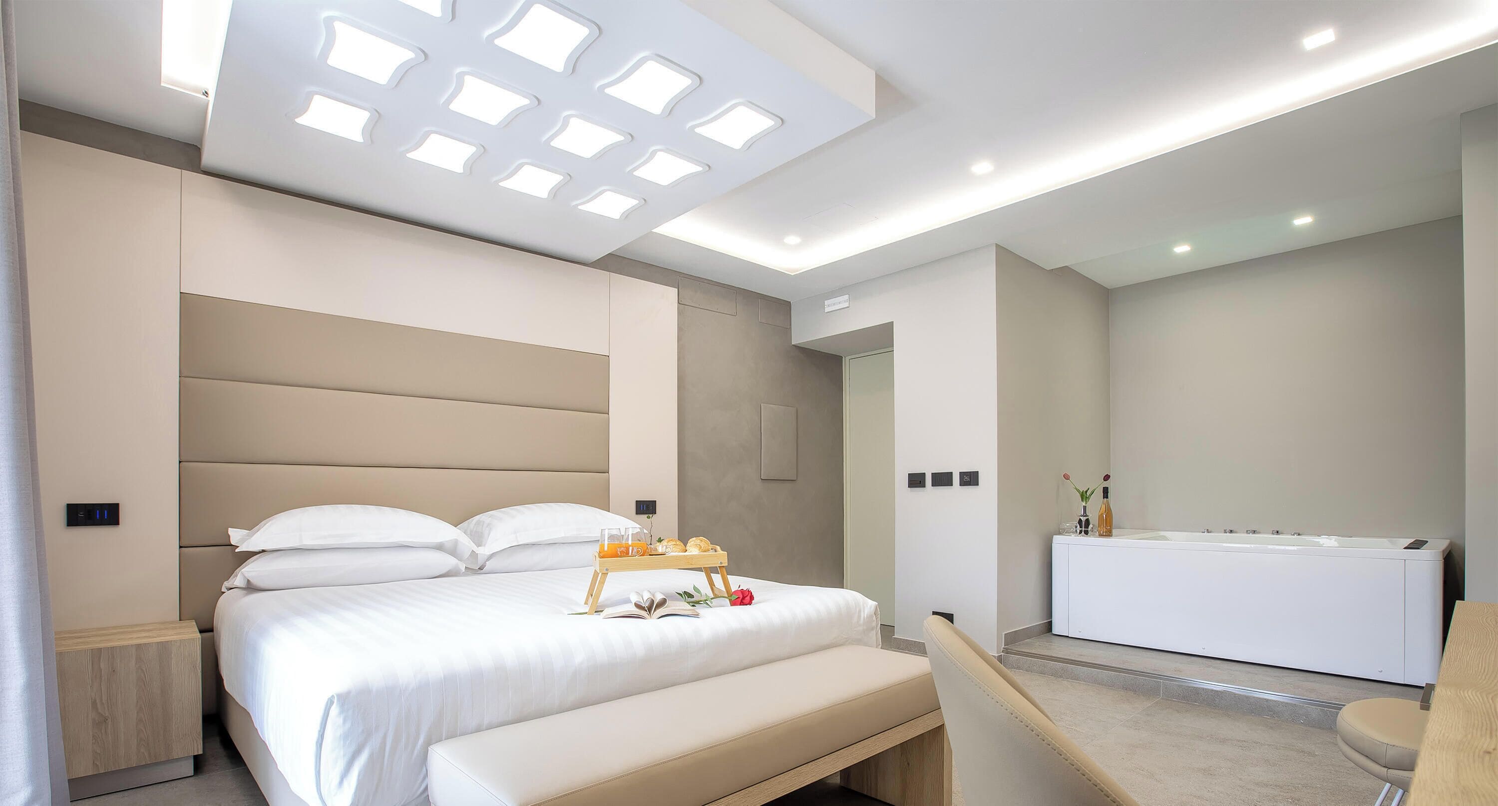 Un dormitorio moderno con una cama grande, una mesita de noche y un banco empotrado.