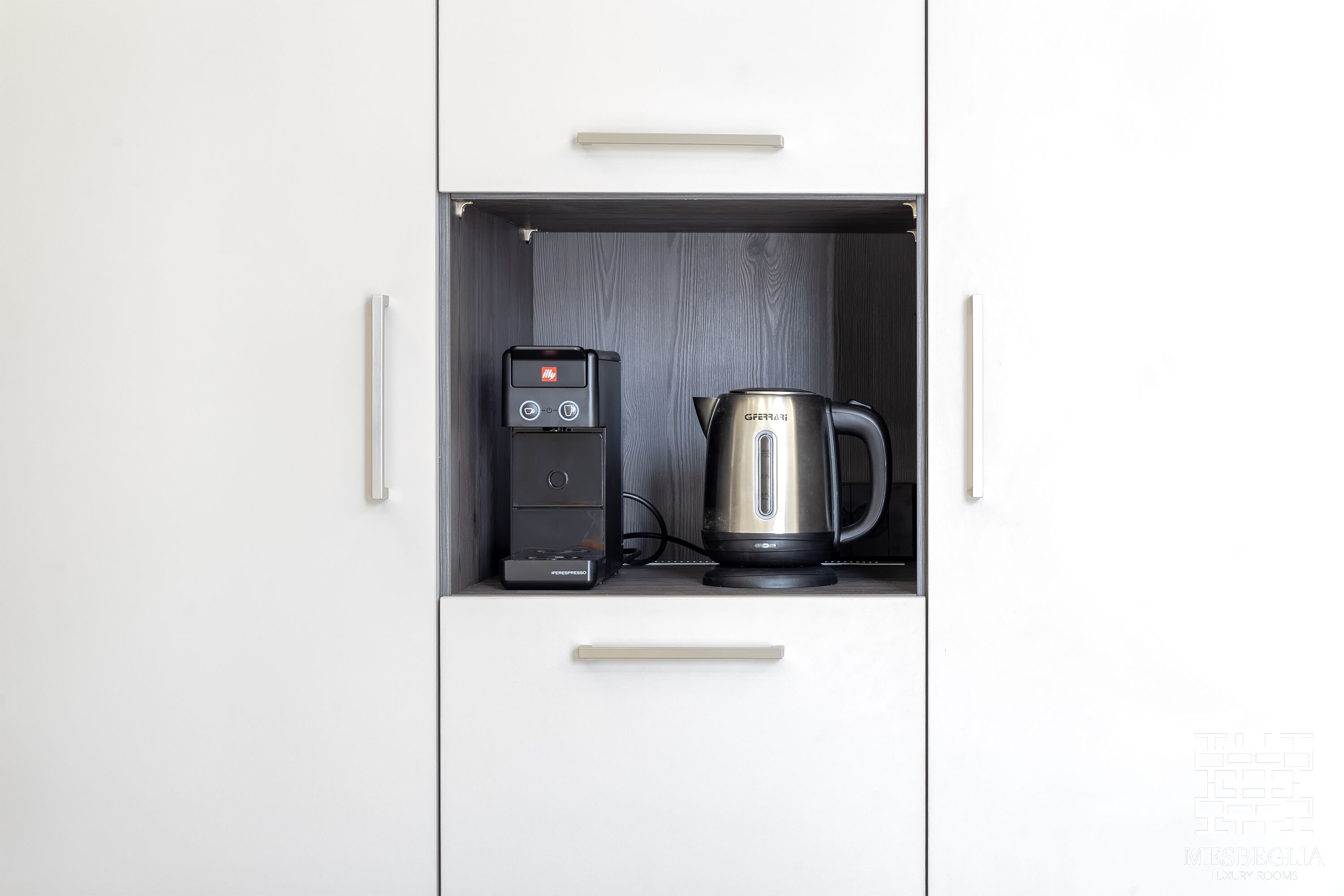 A kitchen with a coffee maker and a kettle.