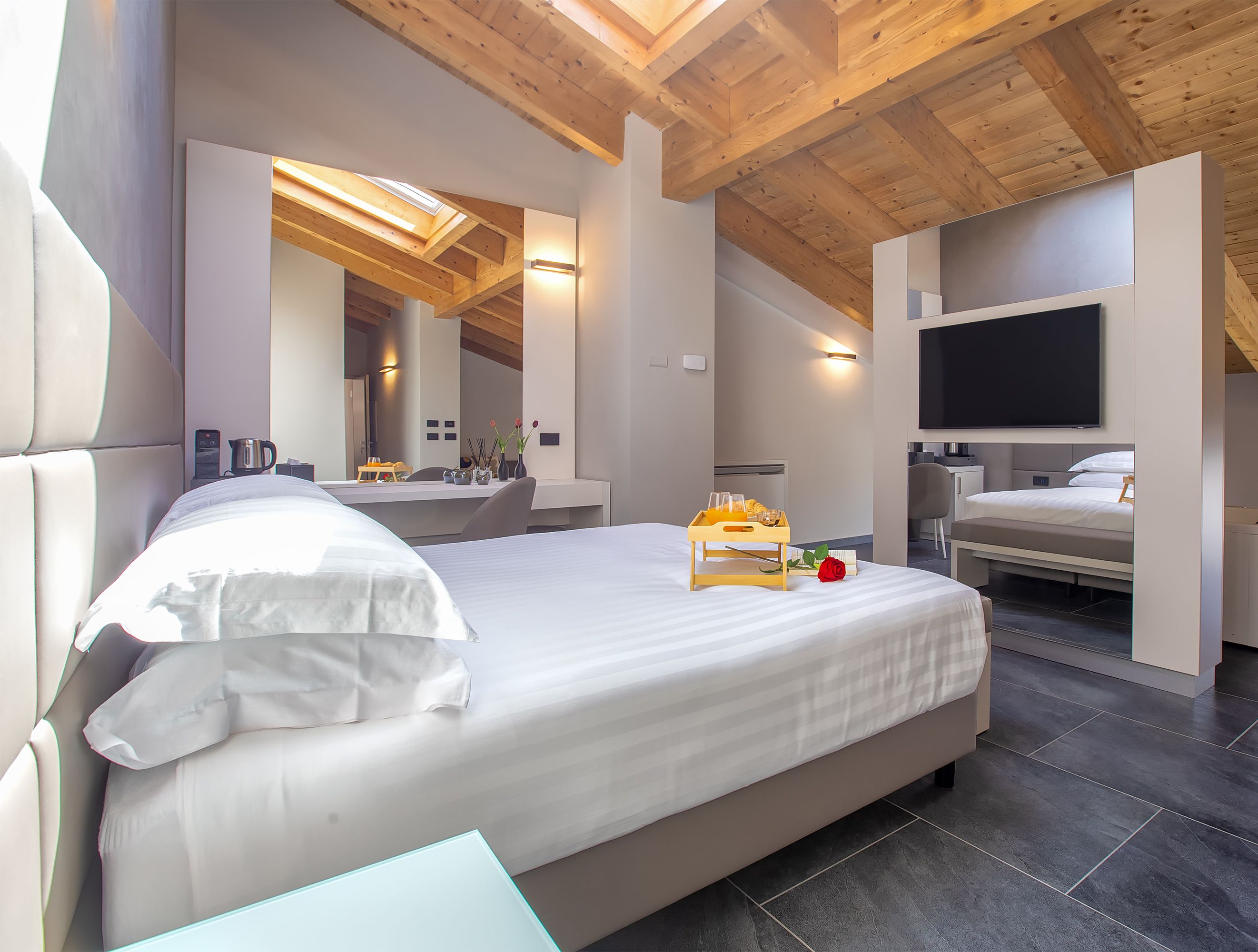 Un dormitorio moderno con una cama grande, un televisor y una bandeja para el desayuno.