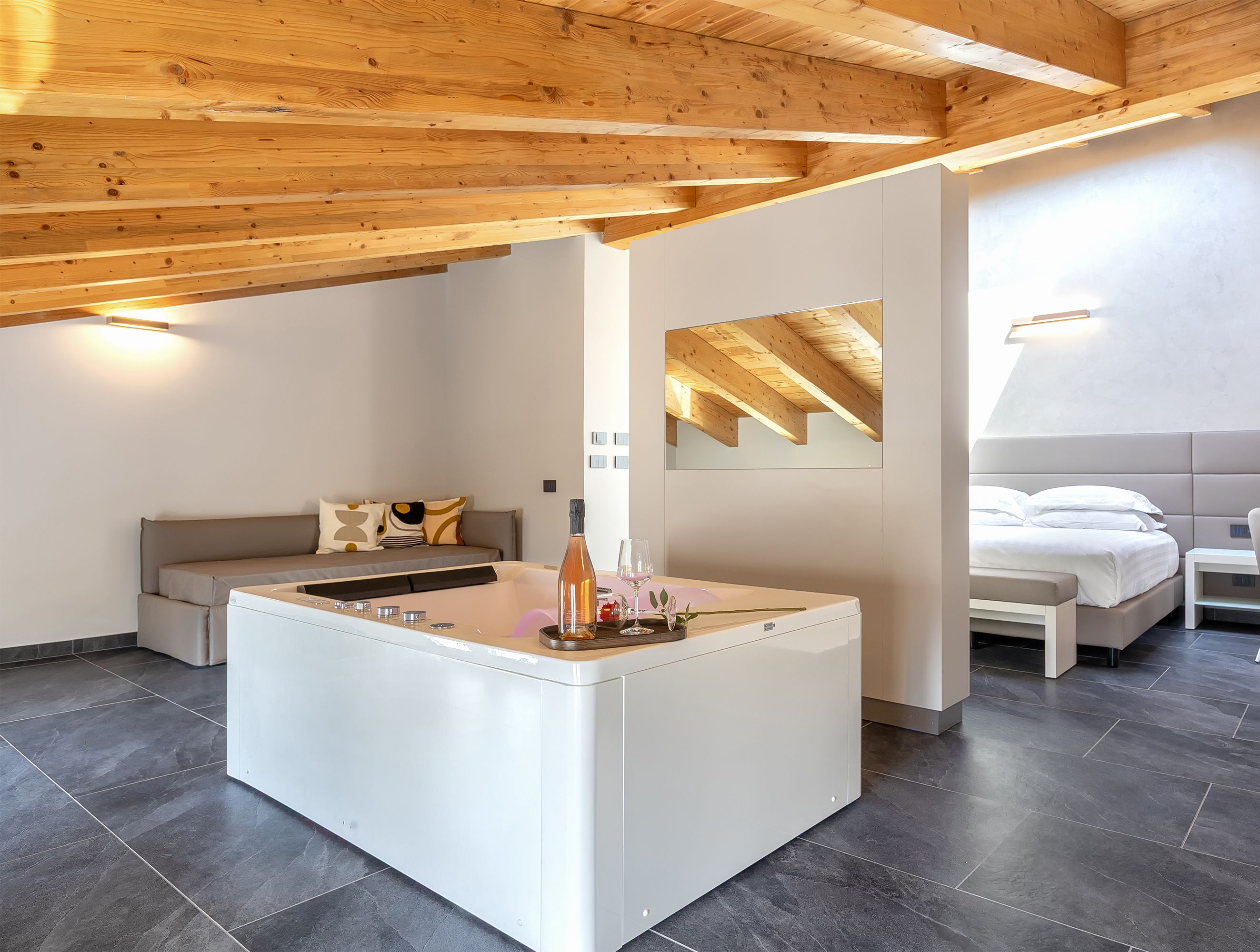 Una habitación moderna y espaciosa con una isla central, un sofá, una cama y una pequeña mesa.