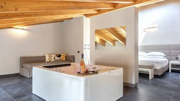 A modern, spacious room with a central island, a sofa, a bed, and a small table.