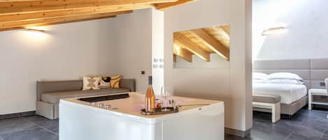 Una habitación moderna y espaciosa con una isla central, un sofá, una cama y una pequeña mesa.