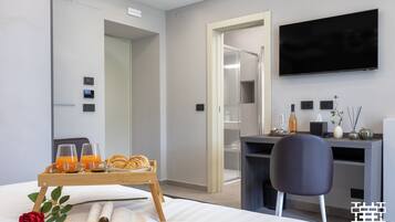 A modern hotel room with a bed, a tray with breakfast items, a rose, and an open book.