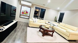 A modern living room with a beige sofa, a glass coffee table, and a flat-screen TV.