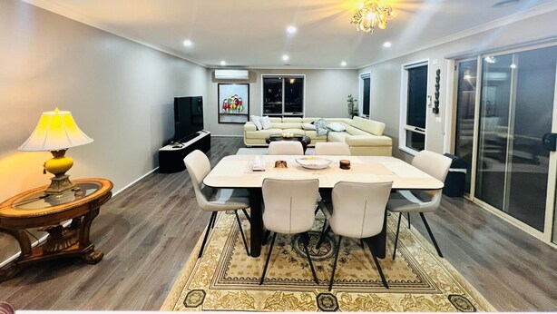 A modern living room with a dining area, a sofa set, and a TV.