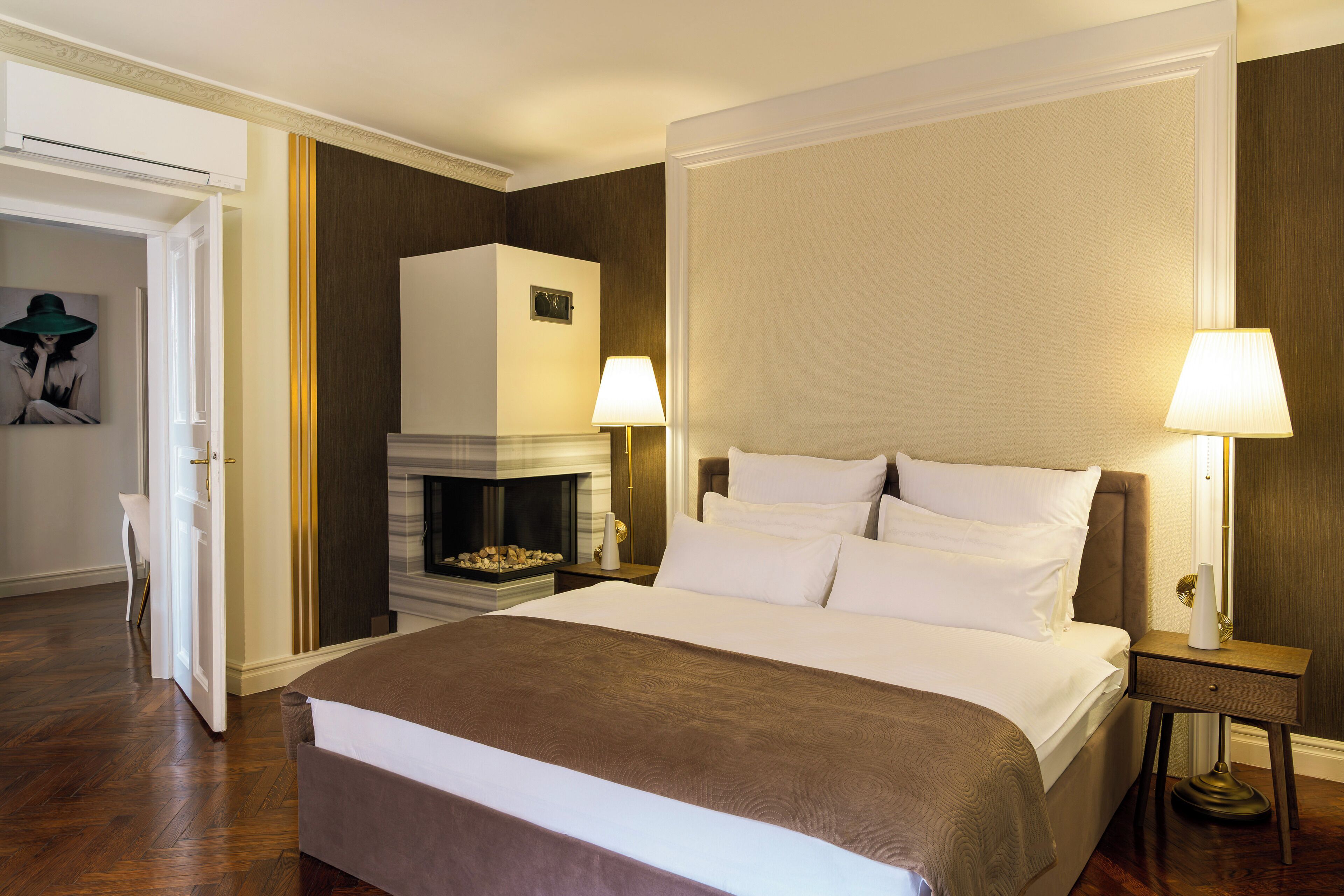 Une chambre d’hôtel avec un grand lit, une cheminée et deux lampes de chevet.