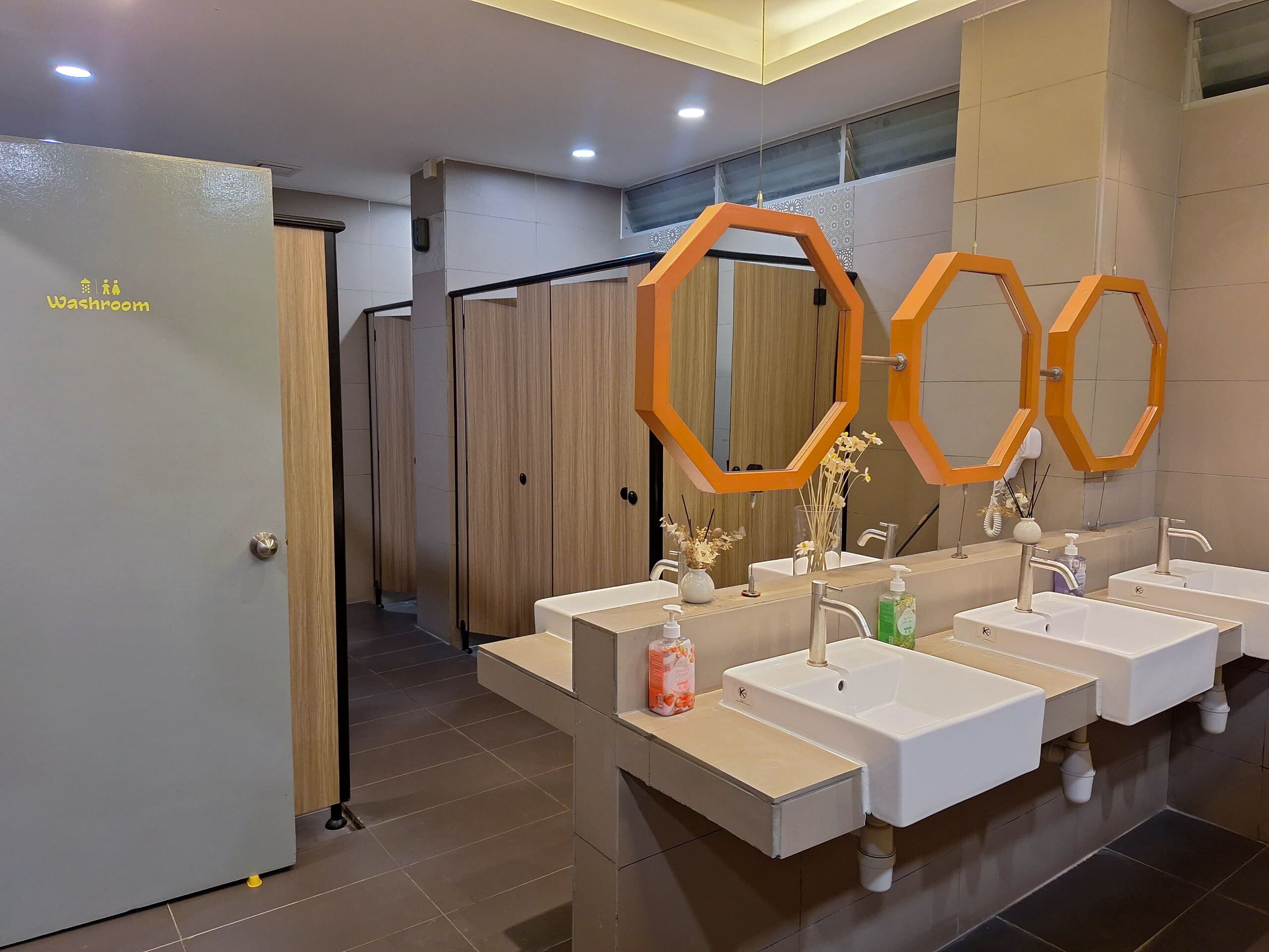Une salle de bain moderne dotée de plusieurs lavabos, d’un espace douche et de toilettes séparées.