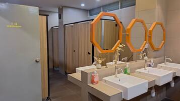 Une salle de bain moderne dotée de plusieurs lavabos, d’un espace douche et de toilettes séparées.