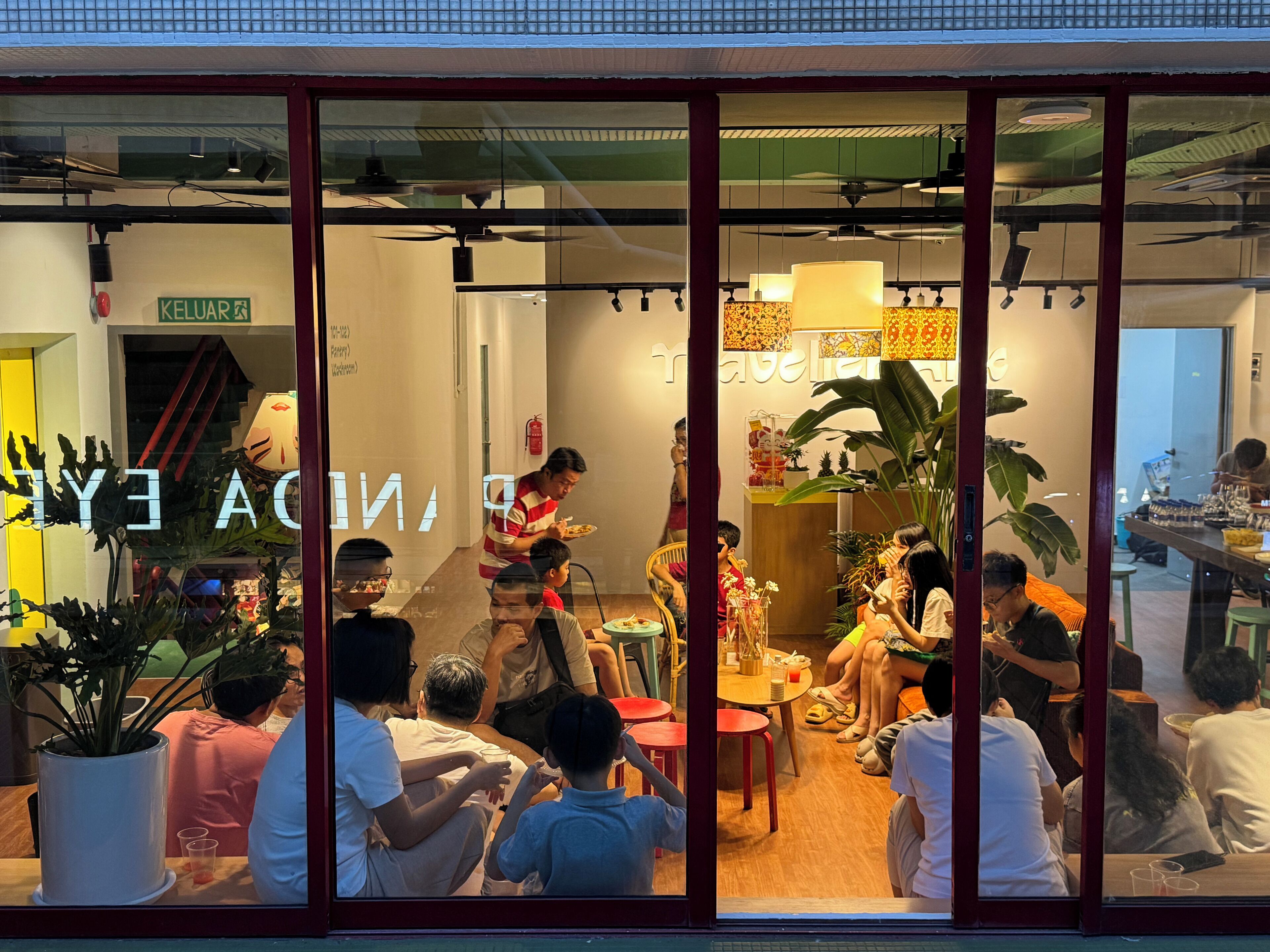 A restaurant with a glass partition, indoor plants, and a group of people dining.