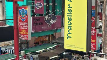 A market area with a prominent yellow sign for "Traveller Ark Hotel" and a "Hari Hari" shop.
